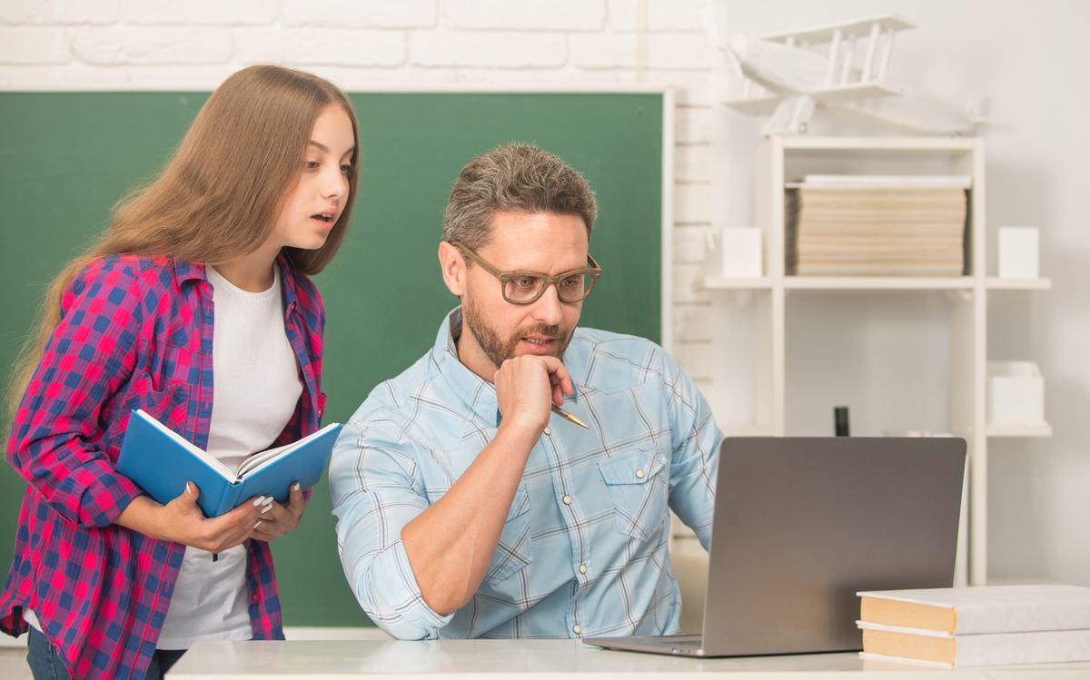 Teacher and student reviewing a business listing on a laptop